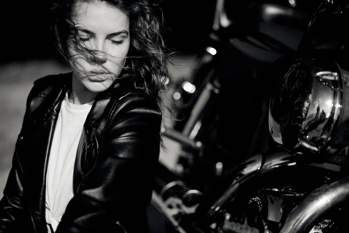 Illustrative stock photograph of a woman beside a motorcycle