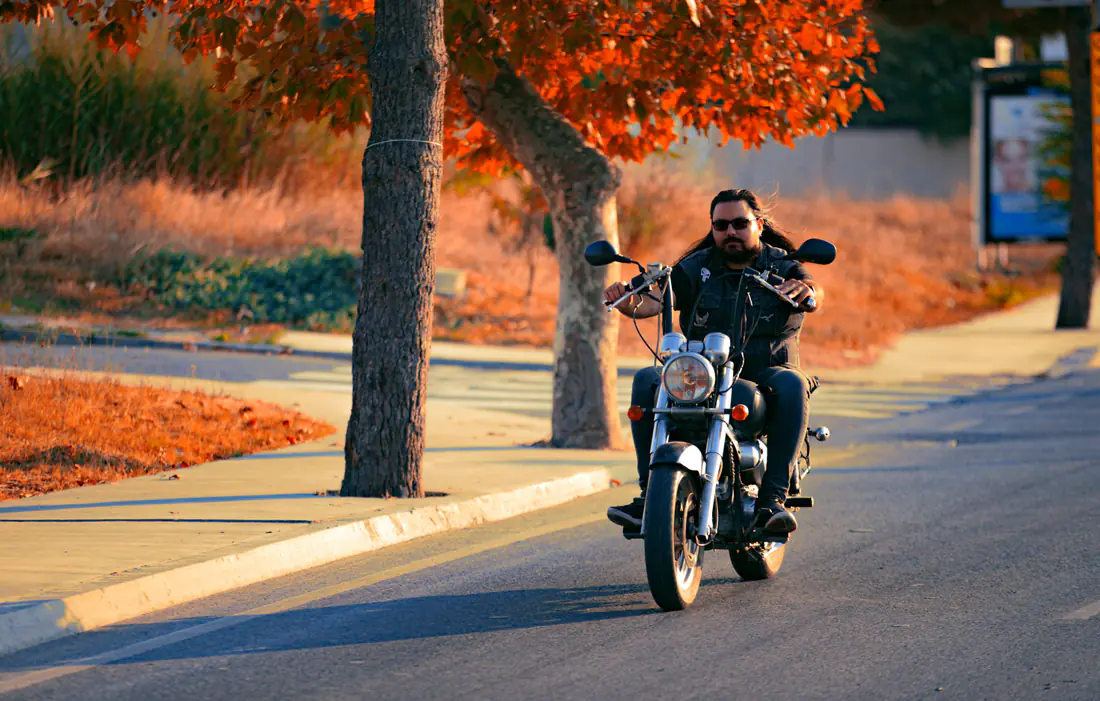 Illustrative stock photograph of a motorcycle rider on a tree-lined road
