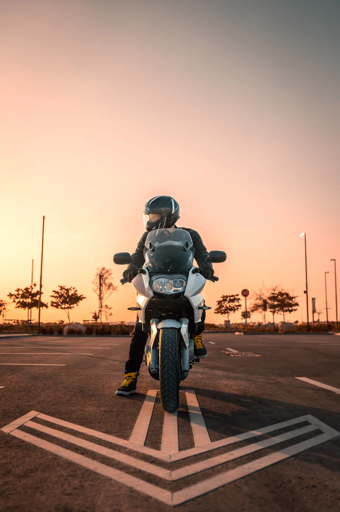 Illustrative stock photograph of a motorcycle rider stopped on a city road at sunset