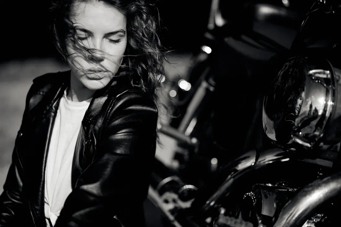 Illustrative stock photograph of a woman beside a motorcycle