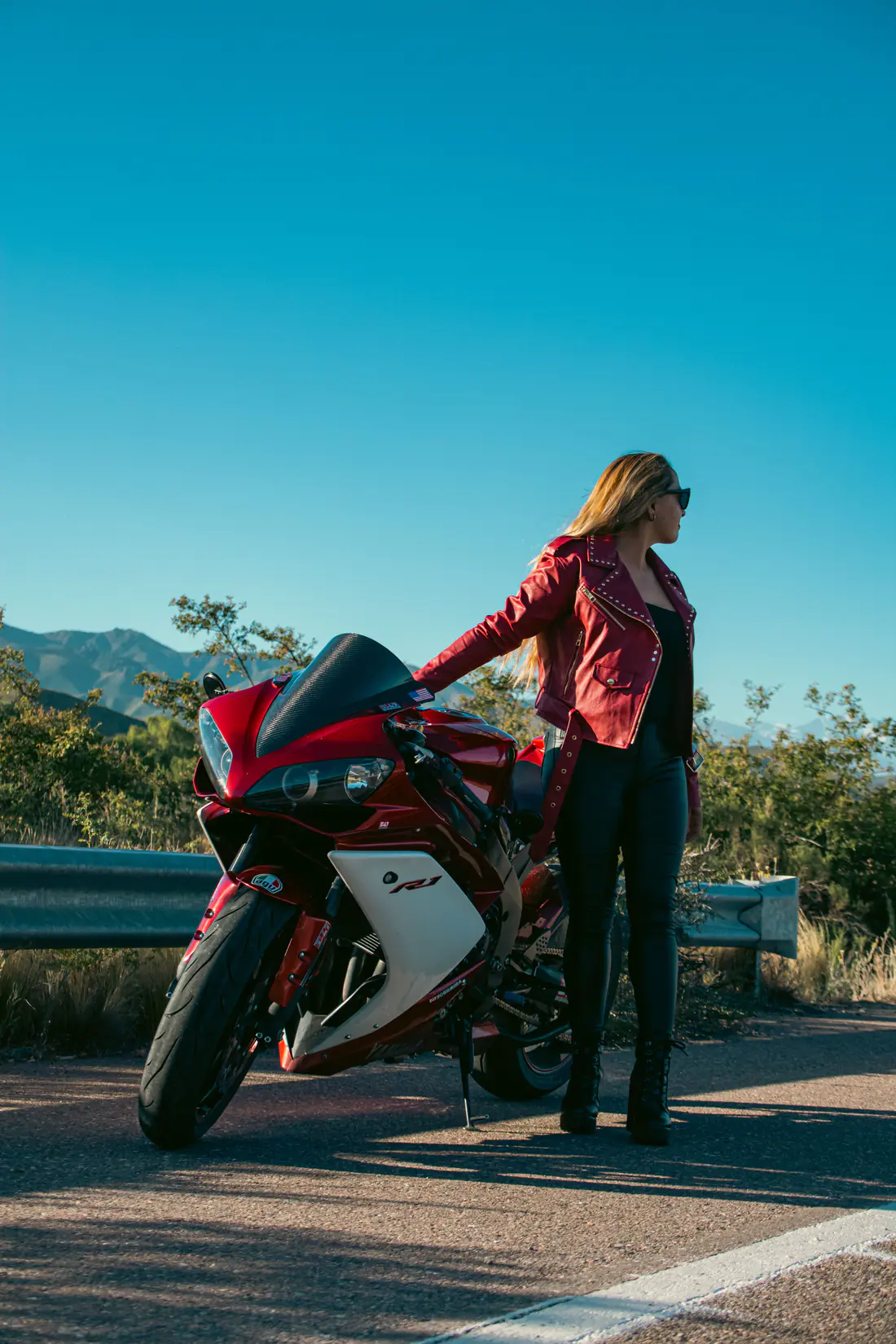 Illustrative stock photograph of a woman standing beside a red sport motorcycle