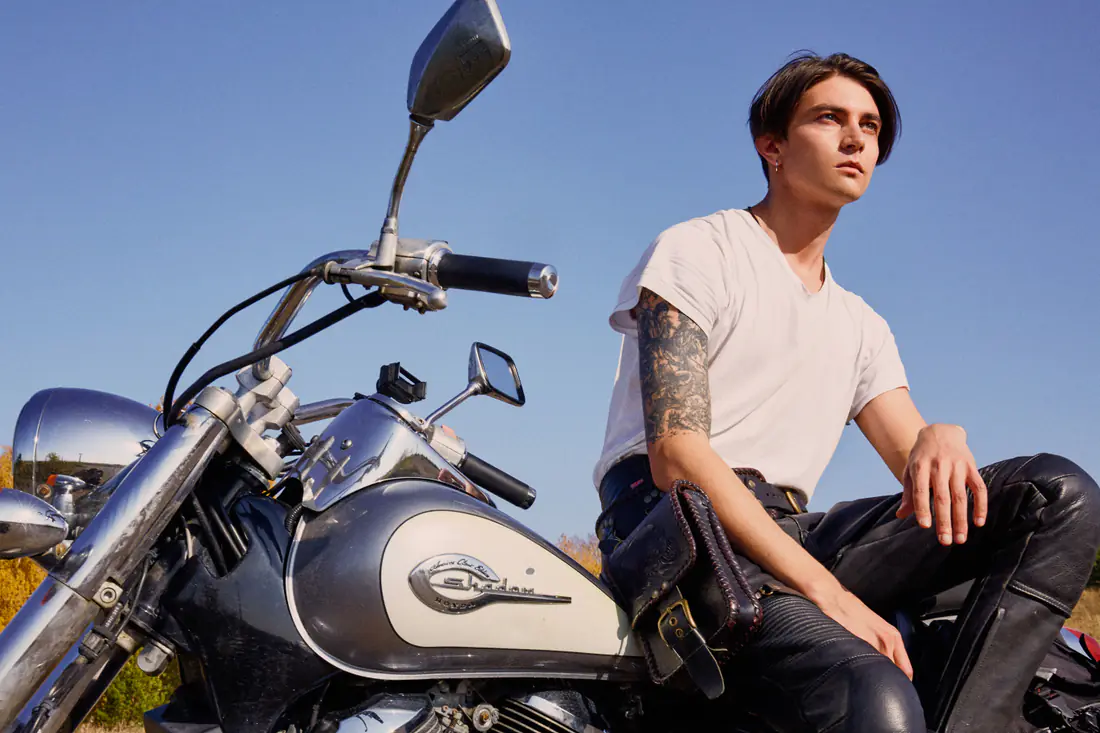 Illustrative stock photograph of an adult seated beside a motorcycle